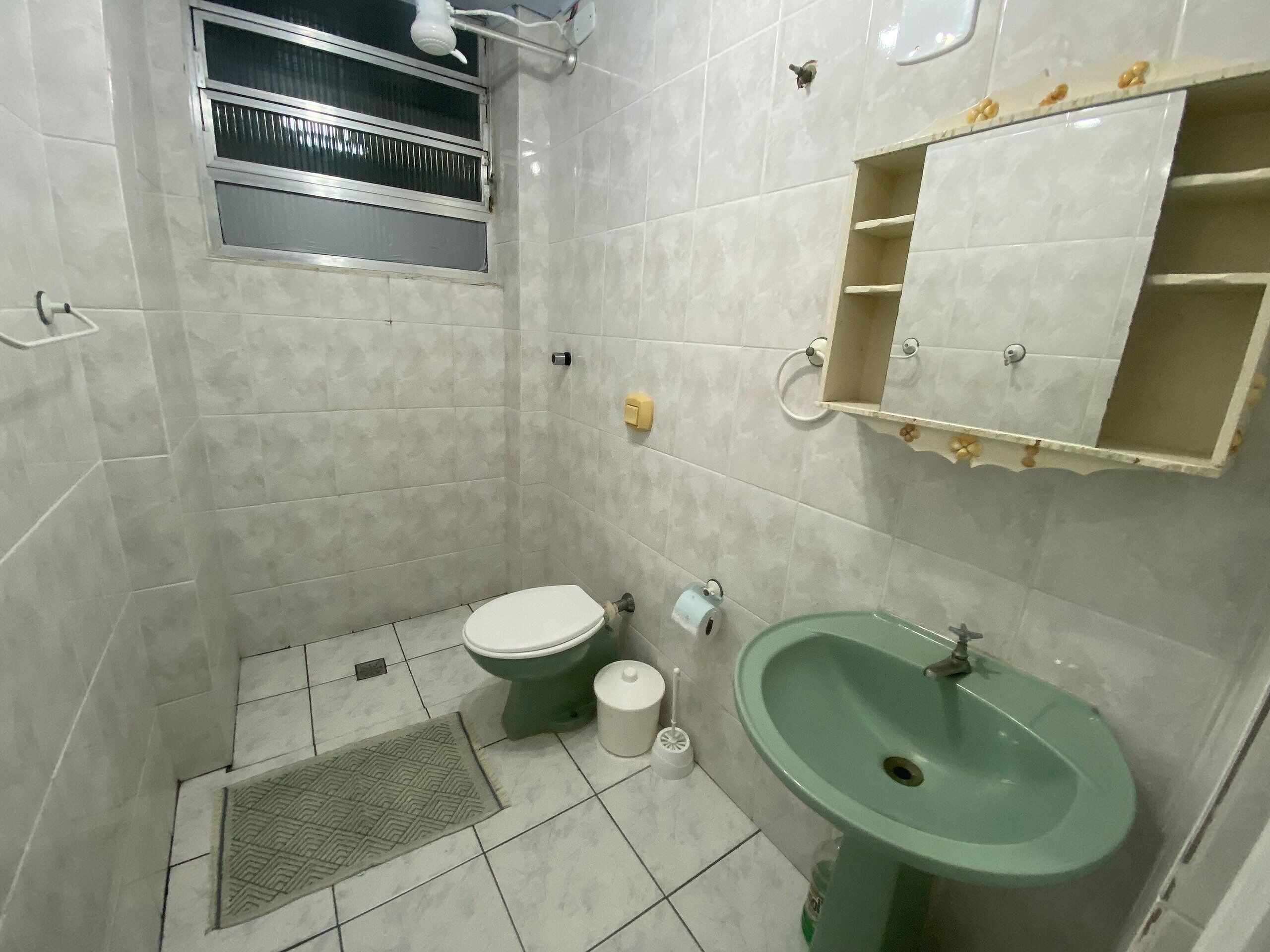 A small bathroom with a toilet, sink, and a window.
