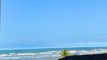 A beach view with a clear sky, waves, and a few people.