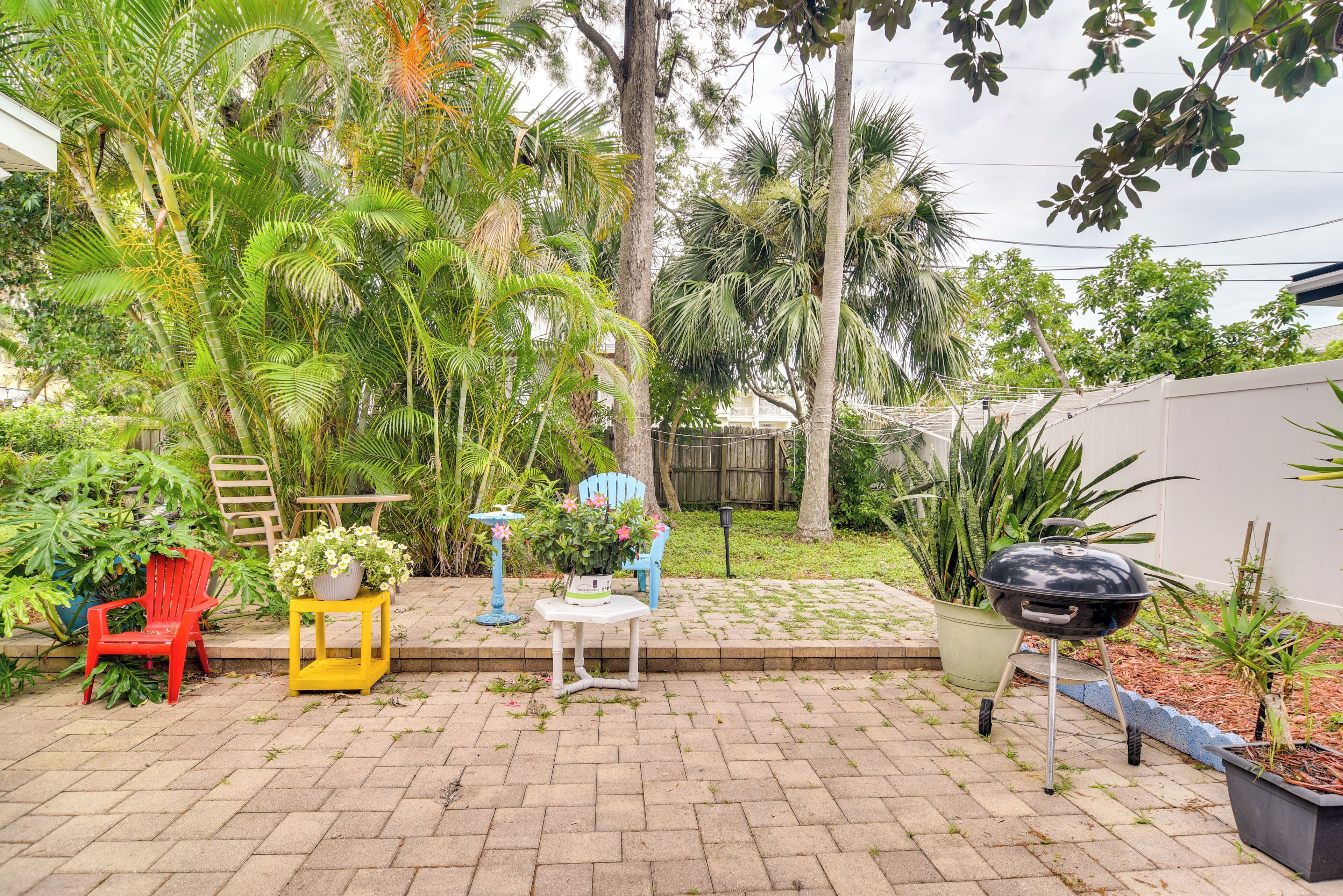 Un patio con una parrilla, sillas y plantas en macetas.