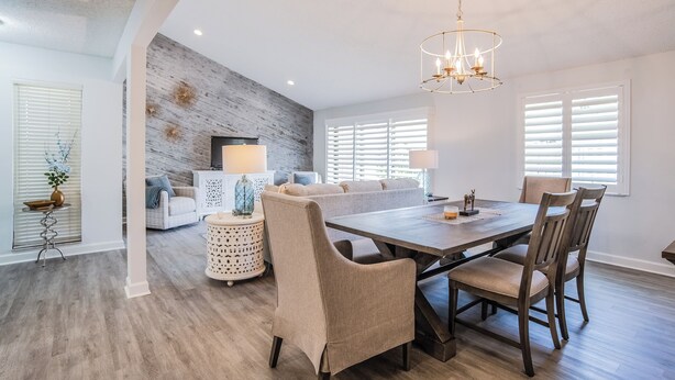 A dining area with a wooden table, beige upholstered chairs, and a chandelier.