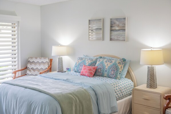 A bedroom with a bed, two bedside tables, a chair, and two wall-mounted lamps.