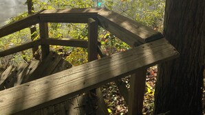 Una terraza de madera con vistas a un cuerpo de agua, rodeada de árboles en tonos otoñales.