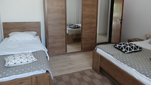 A bedroom with two beds, wooden wardrobes, and a mirror. - Studio Apartment Nikola (Janjina)