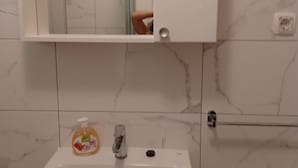 A bathroom with a white sink, a mirror above it, and a bottle of hand soap on the sink. - Studio Apartment Nikola (Janjina)