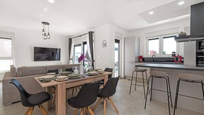 Une cuisine moderne avec un coin repas, comprenant une table en bois, des chaises noires et une grande fenêtre.