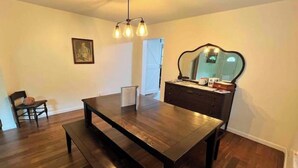 A room with a dark wooden dining table, a bench, a dresser with a mirror, and a ceiling fan. - Cozy Country Home for all ATV Riders! Direct Access to Tackett and Royal Blue! (LaFollette)