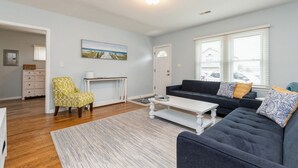 Ein Wohnzimmer mit einem dunklen Sofa, einem gelben Sessel, einem weißen Couchtisch und einem Gemälde an der Wand.
