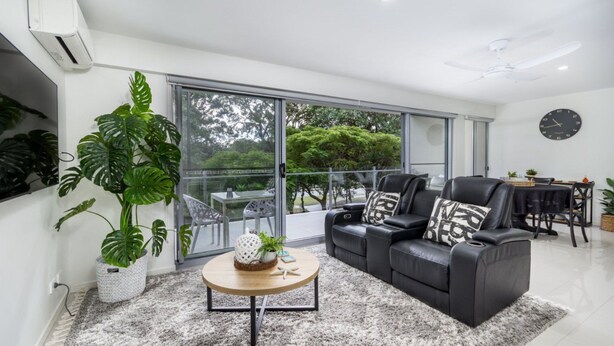 A modern living room with a sofa set, a coffee table, and large windows offering a view of the outdoors. - Modern Beachside Escape (WOORIM)