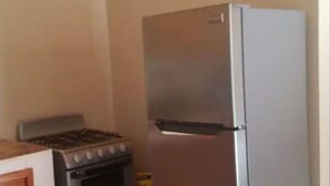 Una cocina con un refrigerador de acero inoxidable, estufa a gas y gabinetes de madera.