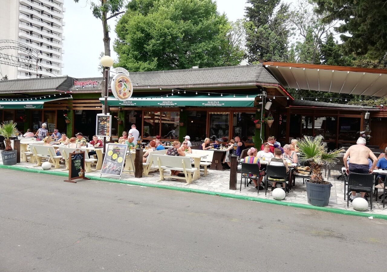 En udendørs café med udendørs siddepladser og et overdækket område.