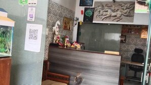 Un espace d’accueil comprenant un comptoir de réception, un tableau encadré, une petite statue et un code QR sur le mur.