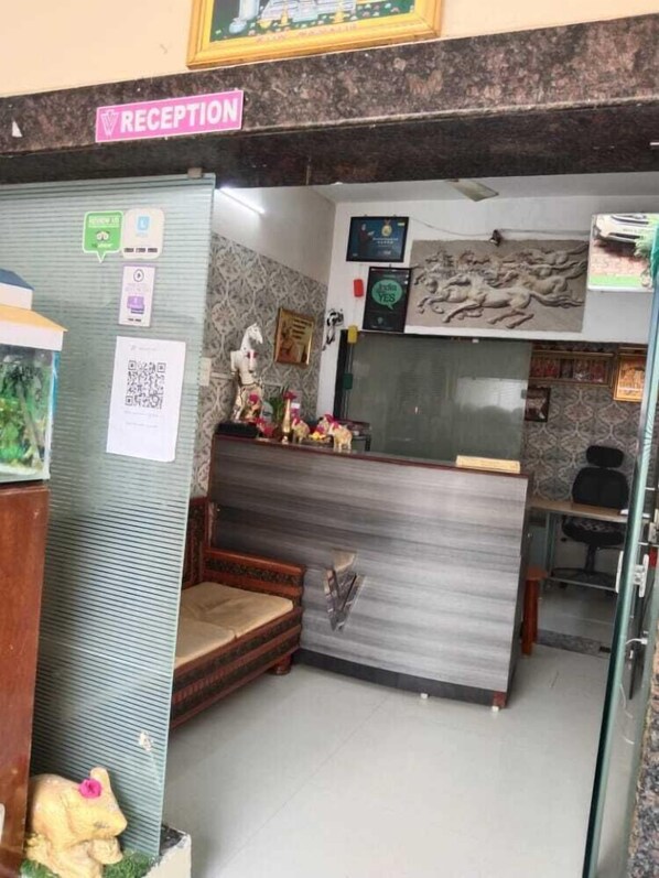 A reception area with a reception desk, a framed picture, a small statue, and a QR code on the wall.