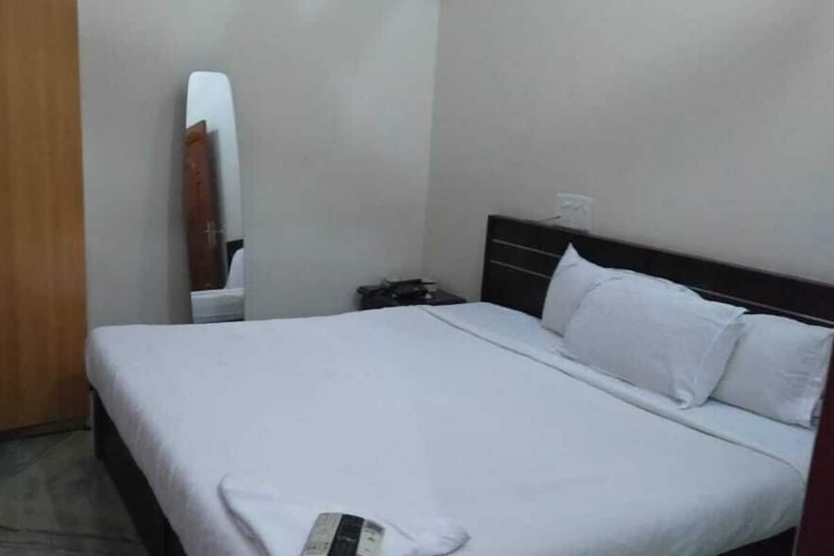 Een slaapkamer met een bed, een houten garderobe en een spiegel aan de muur.