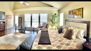 A spacious bedroom with a large bed, a desk, and a television. - South Austin gem - Kickback and relax! (Manchaca)