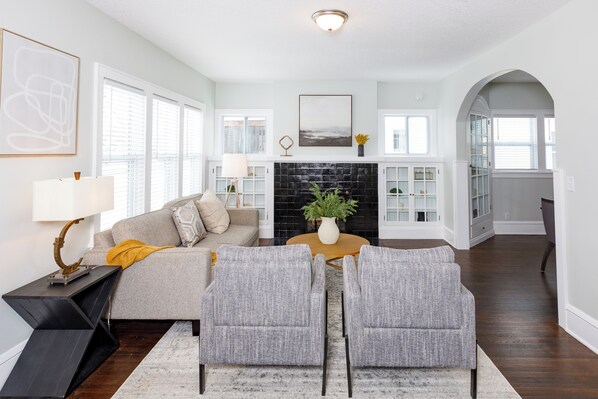 A modern living room with a sofa, two armchairs, a coffee table, and a fireplace.
