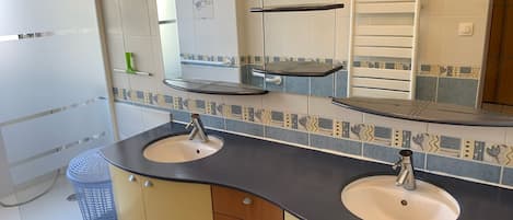 A bathroom with two sinks, a mirror, and a towel rack.