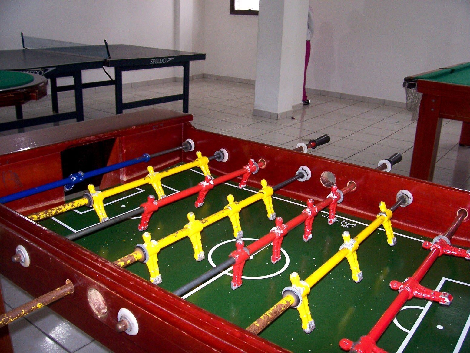 A foosball table with a green playing surface and red and yellow player figures.