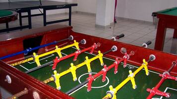 A foosball table with a green playing surface and red and yellow player figures.