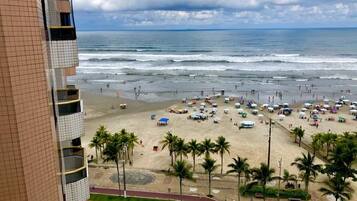 Una playa con gente, sombrillas y palmeras.
