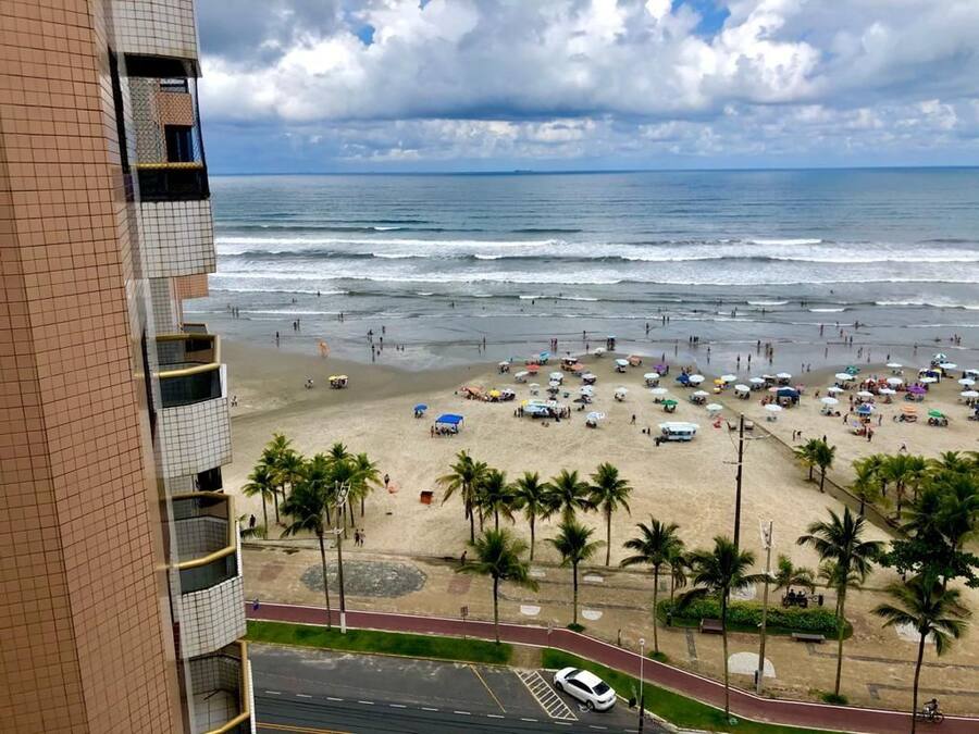 Una playa con gente, sombrillas y palmeras.