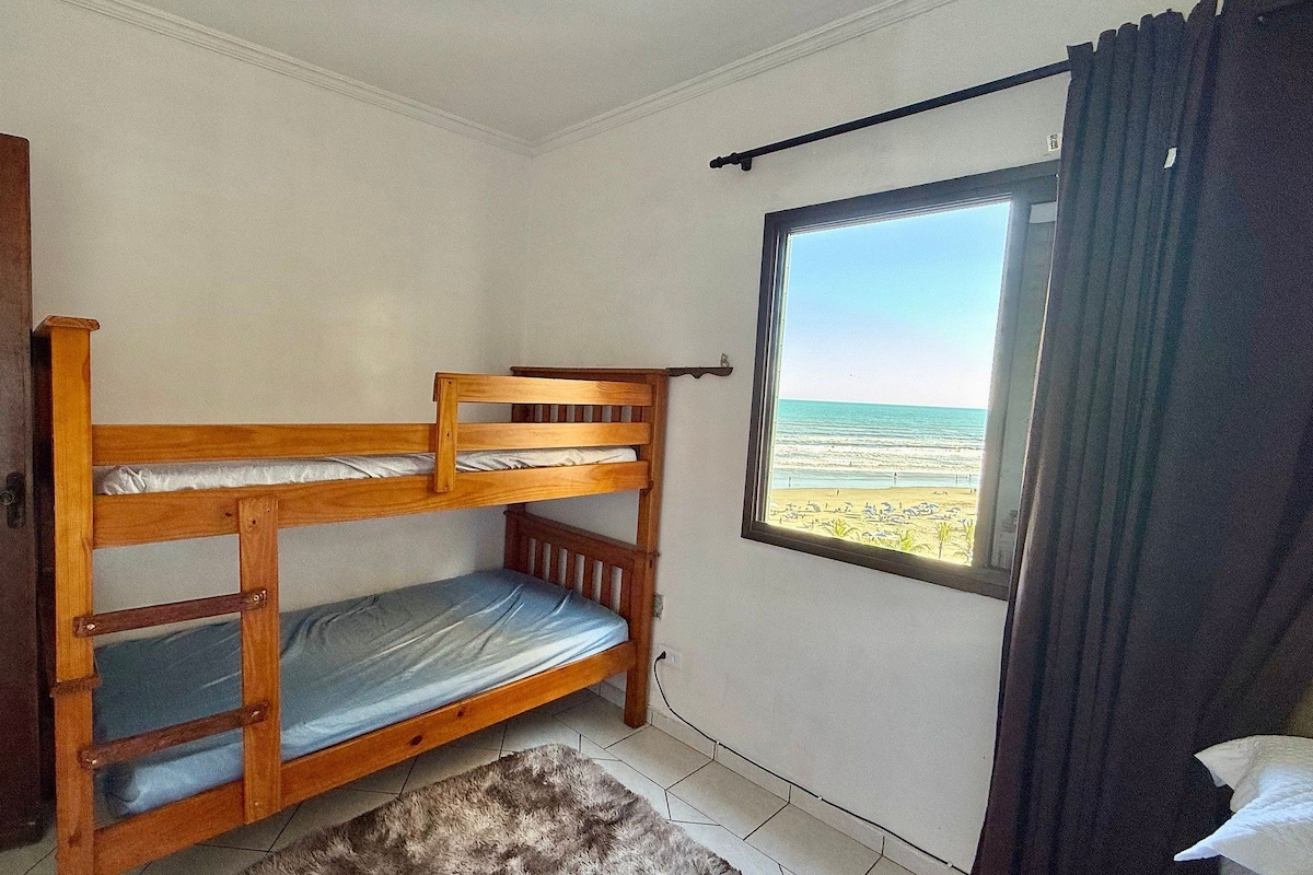 A bunk bed in a room with a window overlooking a beach.