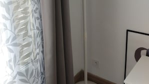 A white floor lamp with a modern design, positioned in a corner of a room with a wooden floor and a white wall. - joseph appartment  (Paris)
