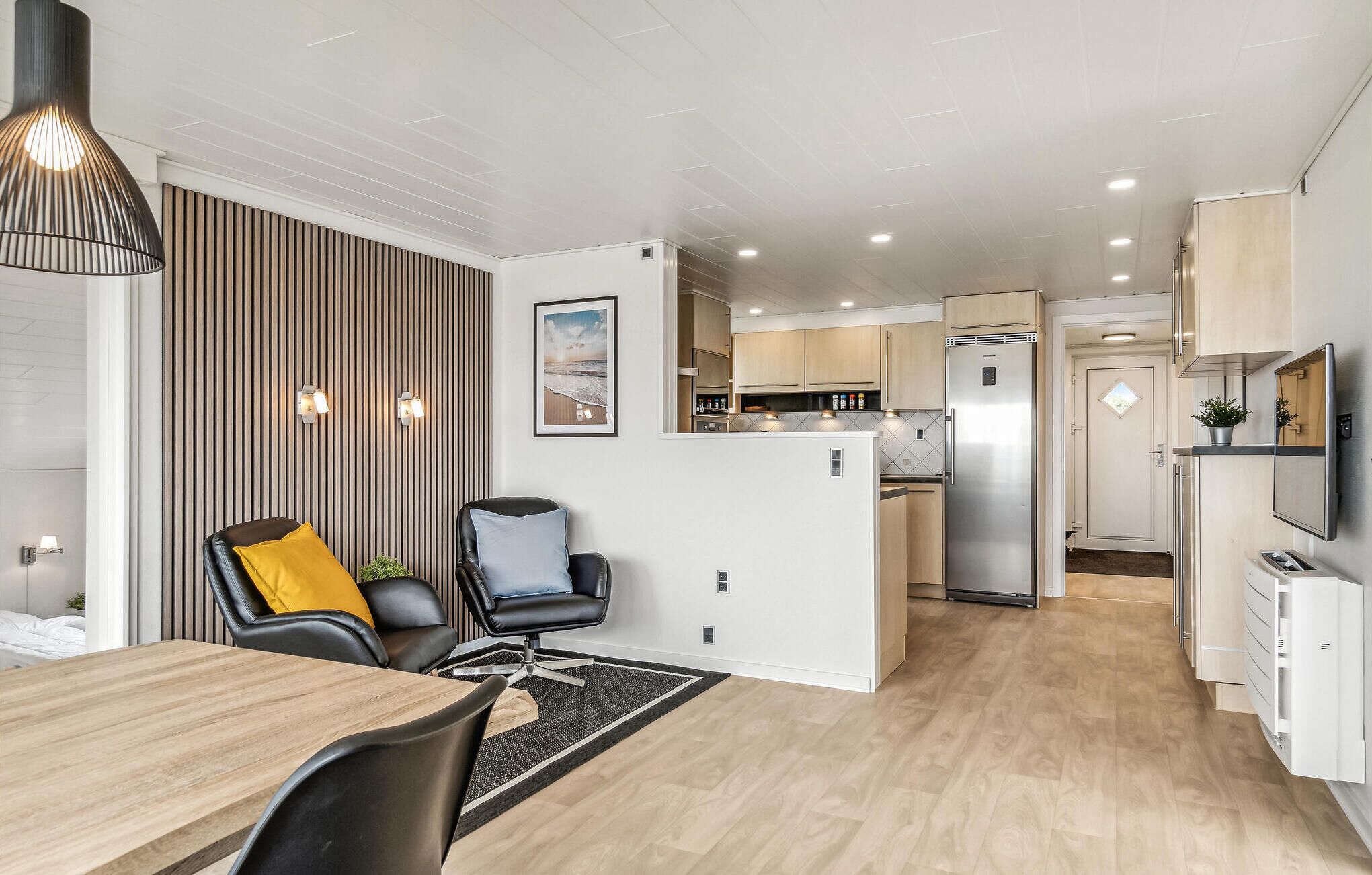 Eine moderne Küche mit Einbaukühlschrank und Essbereich mit Holztisch und Stühlen.