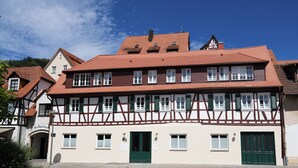A traditional half-timbered building with multiple windows and doors, a clear sky, and a well-maintained garden area. - Vacation apartment "Odenwald" with 2 bedrooms | The crooked house (Heppenheim (Bergstraße))