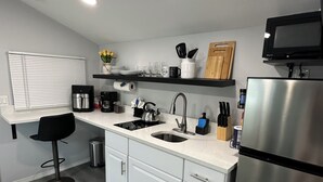Una cocina moderna con refrigerador de acero inoxidable, pileta doble y taburete negro.