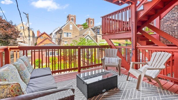 A covered outdoor deck with a sofa, two Adirondack chairs, and a coffee table. - REMODELED Splendid Flat in Bucktown +Back Porch, Ranked GUEST FAVORITE! Pets OK! (Chicago)