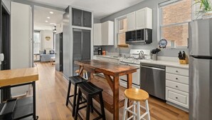A modern kitchen with white cabinets, a wooden island, and stainless steel appliances. - REMODELED Splendid Flat in Bucktown +Back Porch, Ranked GUEST FAVORITE! Pets OK! (Chicago)