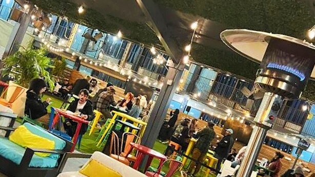 Un espace de convivialité intérieur comprenant des coins salon, des tables et un luminaire central.