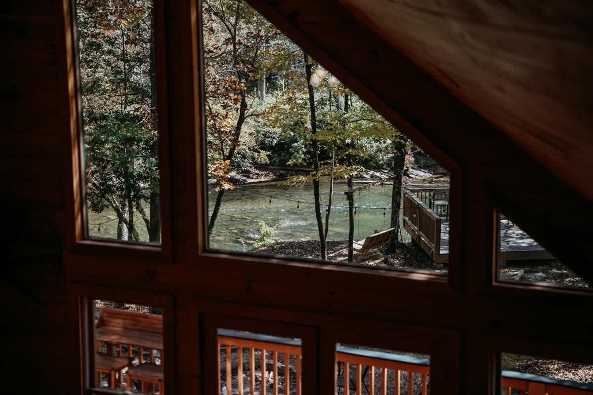 A cabin with multiple windows, a wooden deck, and a view of a forested area.