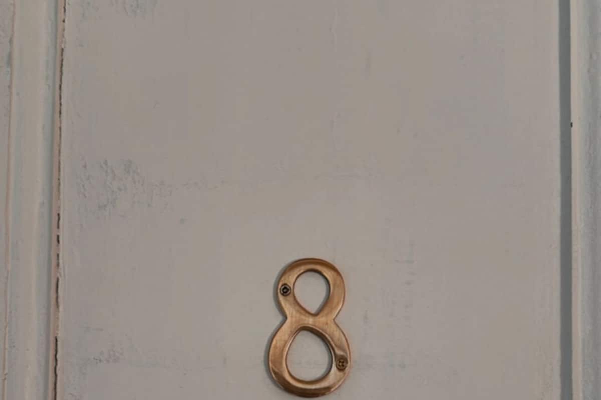 Una puerta con un pomo de bronce con el número ocho.