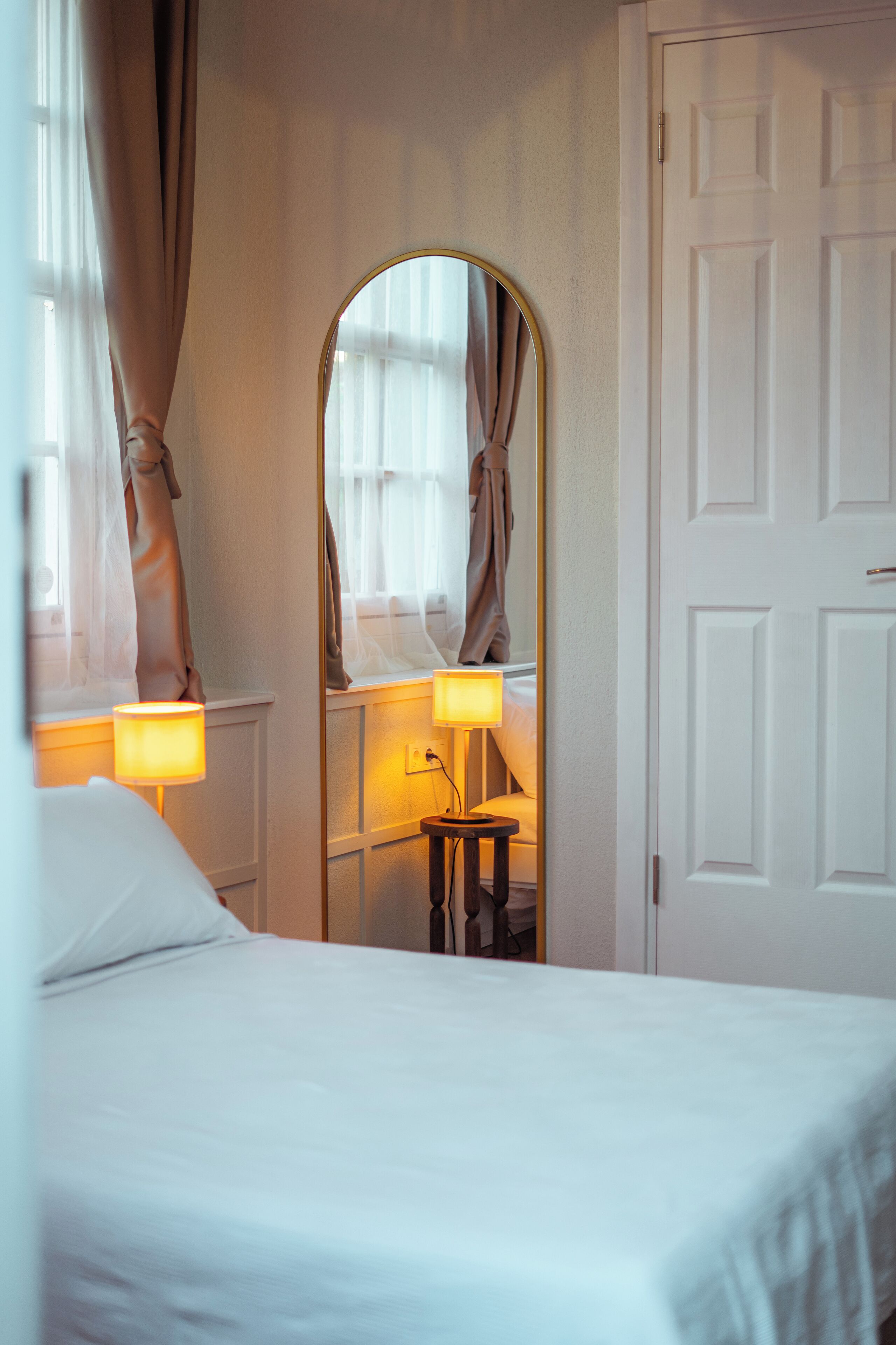Una habitación de hotel con una cama, un espejo y una puerta.