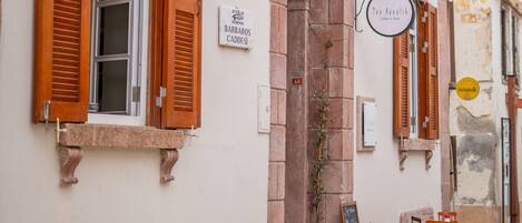 A street-side cafe with outdoor seating, a signboard, and a small entrance.