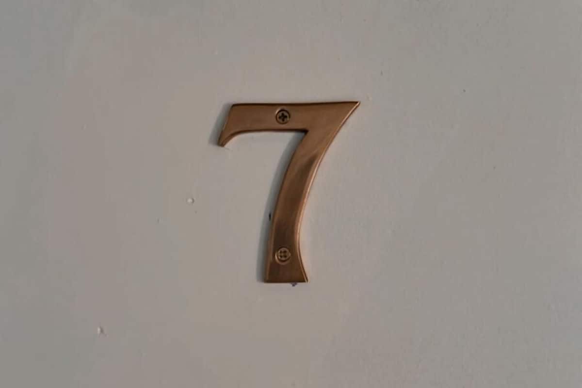 Un número 7 de bronce sobre un fondo sencillo.