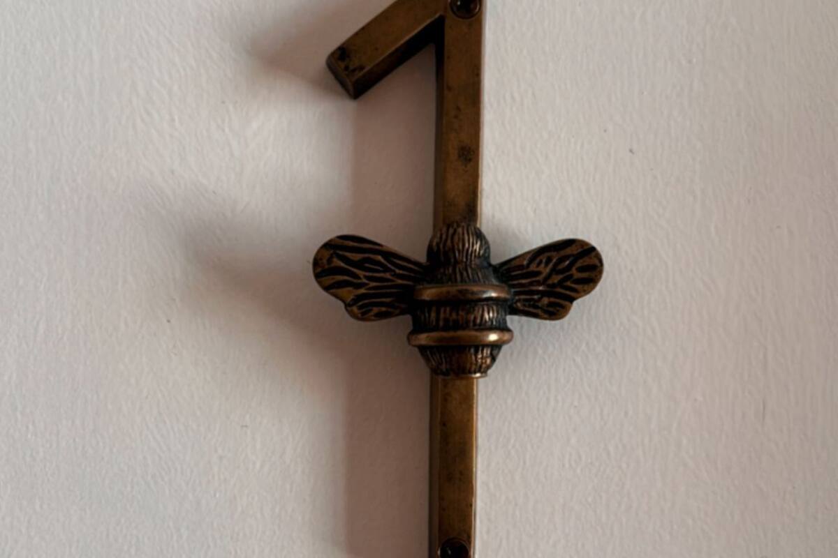 Un número 1 de bronce con detalles alados, fijado a la pared.