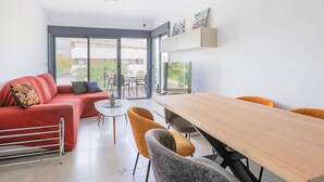 Una sala de estar moderna con un sofá rojo, una mesa de comedor de madera y un ventanal con vistas al exterior.