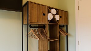 A wooden storage unit with shelves and hanging space for towels and clothes.
