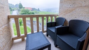 A balcony with a stone railing, two wicker chairs, and a small table.