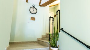 A staircase with a clock, a sign, and a potted plant.