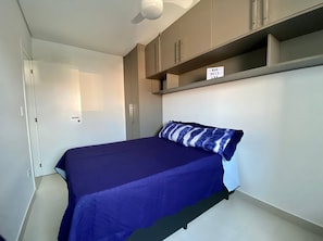 A bedroom with a bed, a wardrobe, and a shelf with a sign. - Flat Unitá Homestay (Praia Grande)