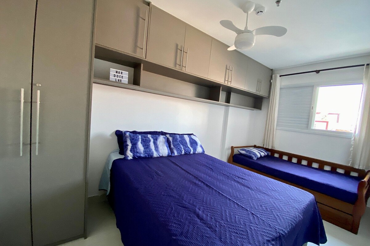 A bedroom with a bed, a wooden bench, a wardrobe, and a ceiling fan.