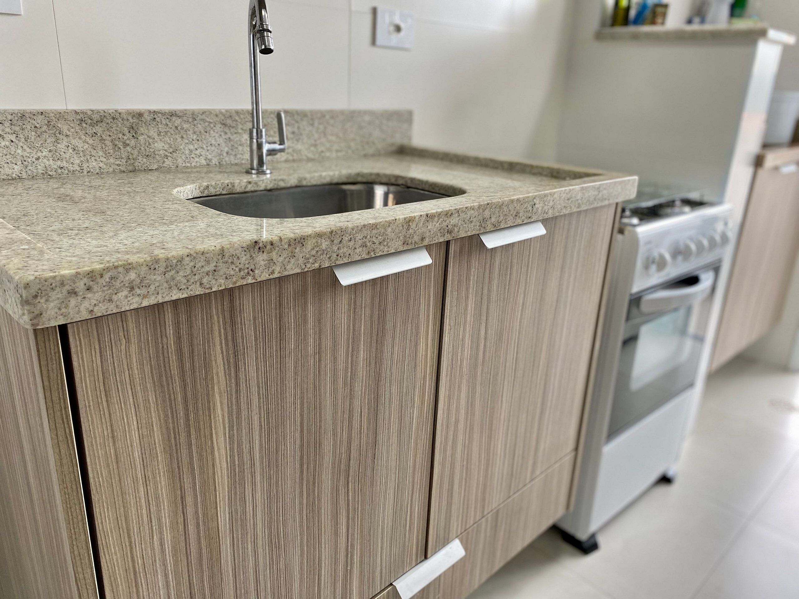 Una cocina con encimera de granito, pileta de acero inoxidable, armarios de madera y horno integrado.