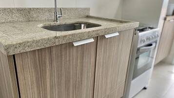 Una cocina con encimera de granito, pileta de acero inoxidable, armarios de madera y horno integrado.