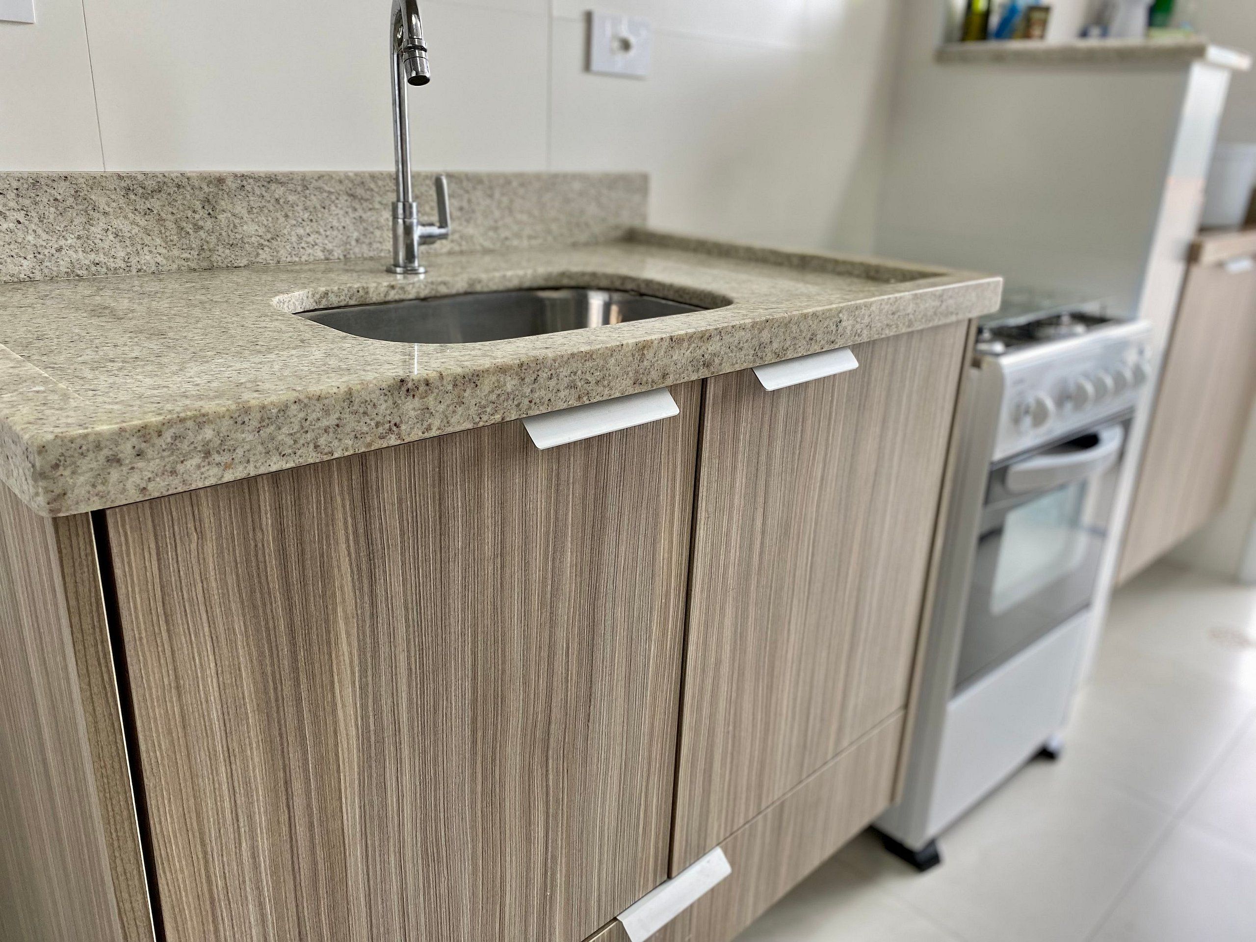A kitchen with a granite countertop, stainless steel sink, wooden cabinets, and a built-in oven.