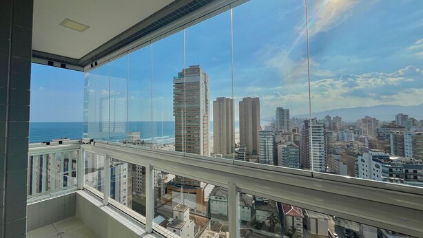 A high-rise building with large windows, a view of the cityscape, and a clear sky. - Flat Unitá Homestay (Praia Grande)