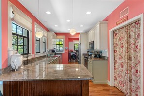 A modern kitchen with a central island, built-in appliances, and a pantry area.