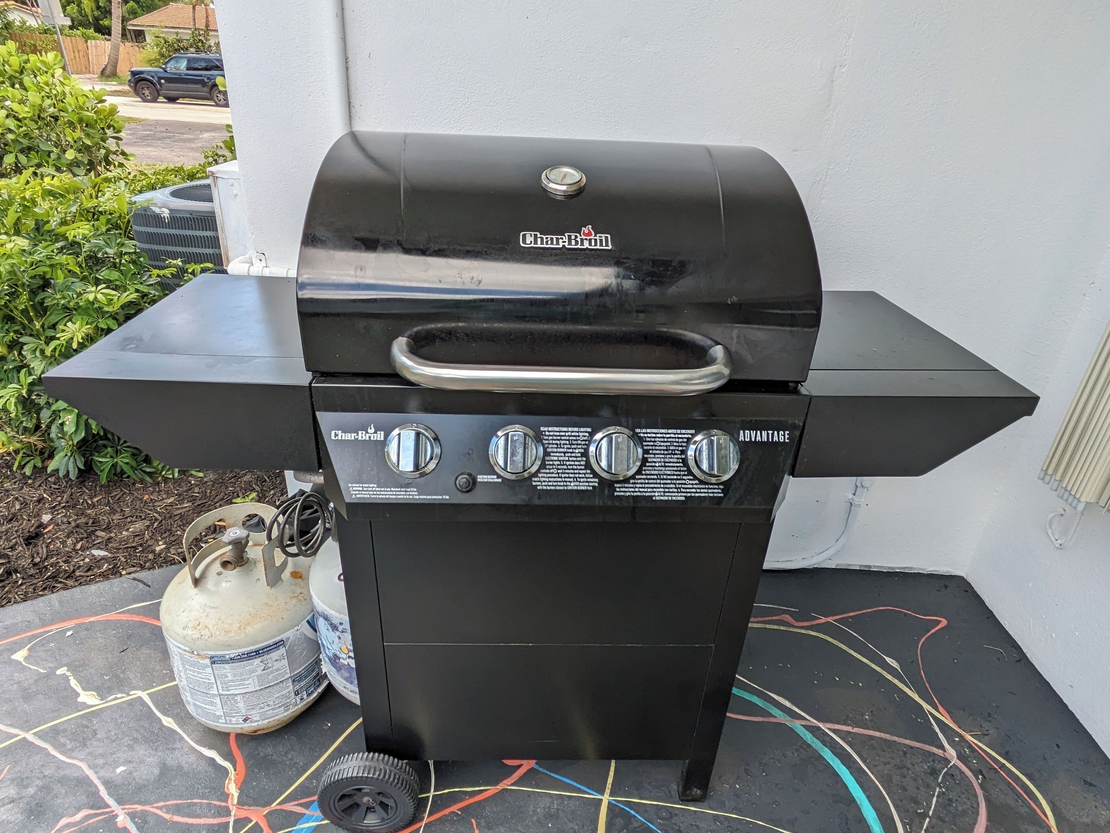 A Char-Broil Advantage portable grill with a gas tank and a control panel, placed on a concrete surface with colorful lines.